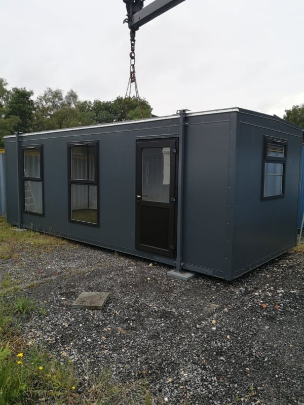 grey modular building being placed down by crane